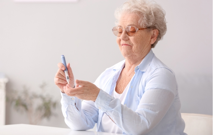A senior woman with diabetes checking her blood sugar level with a blood glucose test on her finger tip