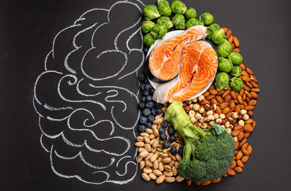 A half drawing of a brain on a chalkboard paired with healthy food that supports brain function filling the other side of the drawing