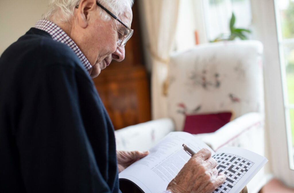 a senior man does a crossword puzzle as an exercise to train memory