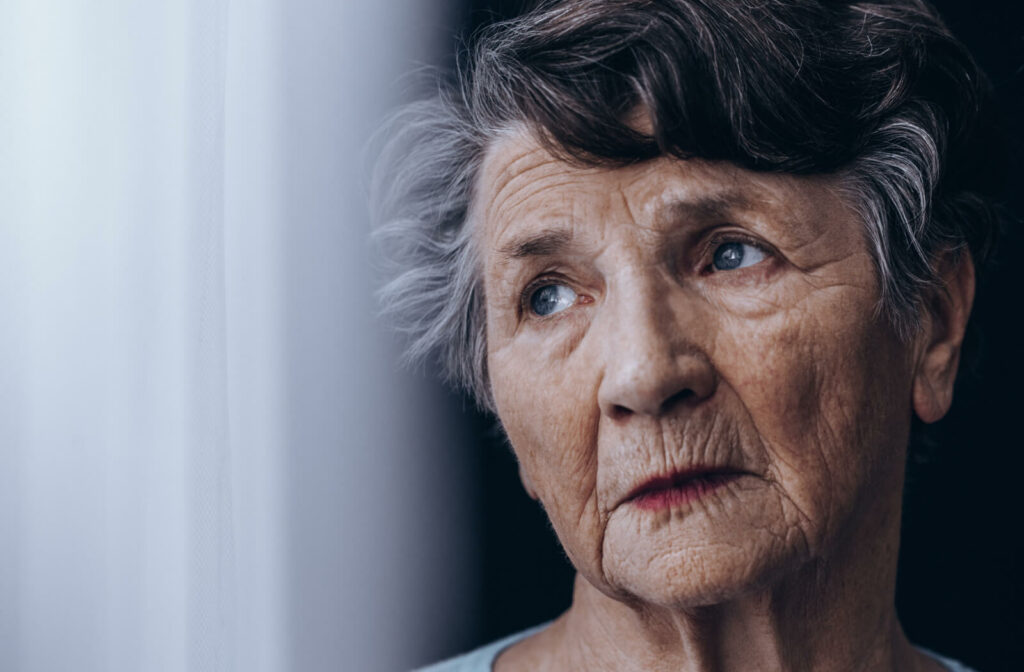 a closeup of a senior womans face looking out a window